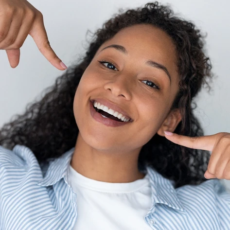 Happy woman pointing at her beautiful teeth