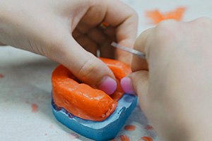 A dental technician creating a wax mold
