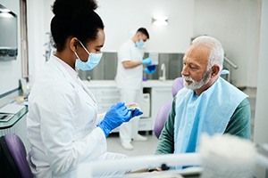 A dentist showing dentures to an older man