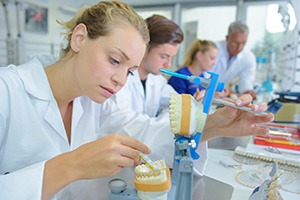 A dental technician further refining a denture