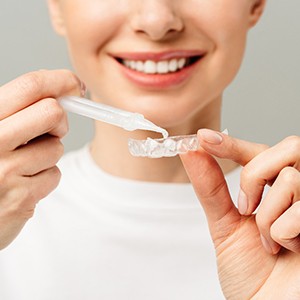 Woman using custom tray for teeth whitening at home